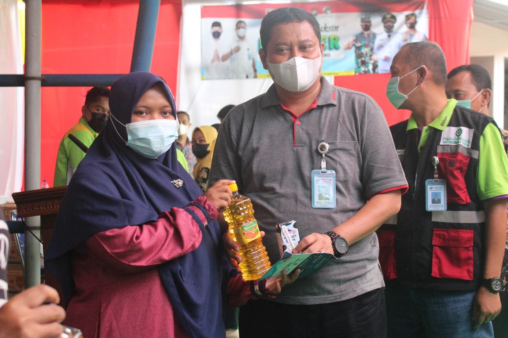 Direktur Koperasi Kareb menyerahkan satu botol minyak goreng kepada warga Bojonegoro yang telah mendapatkan vaksin booster, Sabtu, 12 Maret 2022. (Sumber foto: Dokumentasi AMTI)